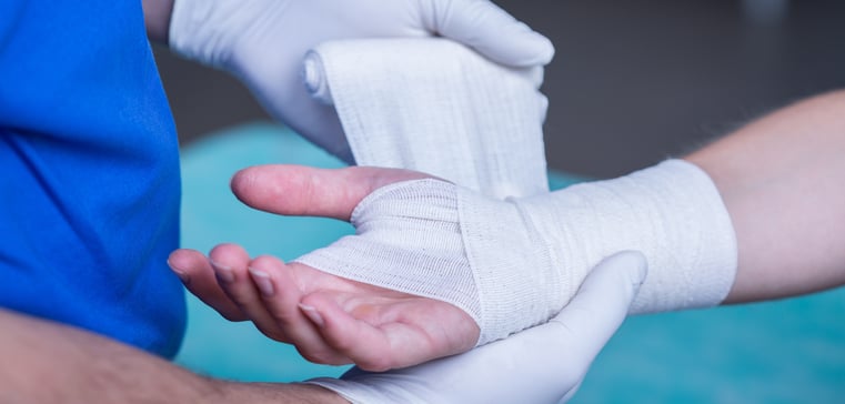 Close-up of male doctor bandaging a fractured hand