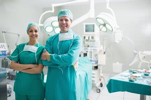 Surgeons standing up while smiling in an operating theatre